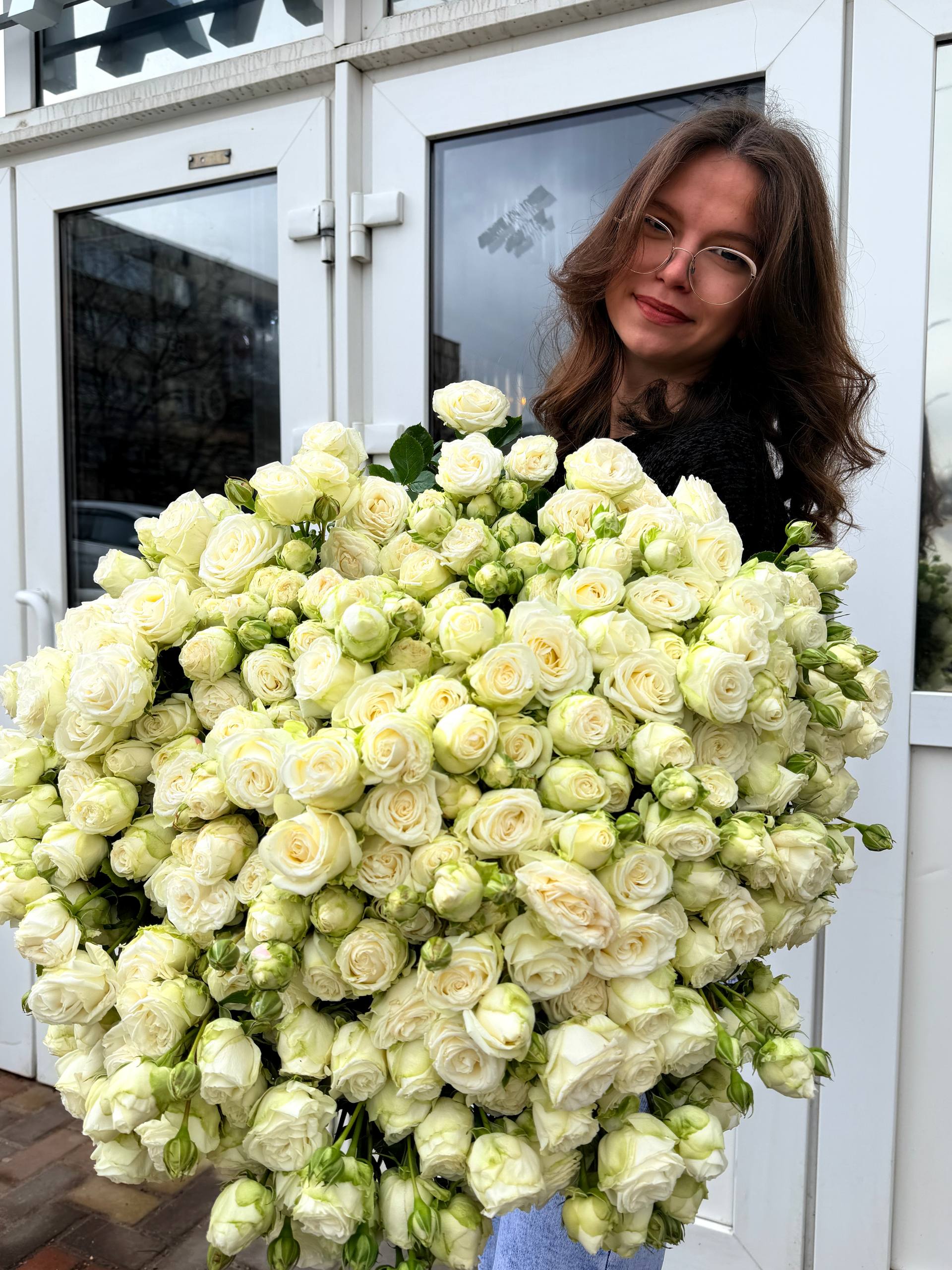 Букет из белых кустовых роз в руках флориста